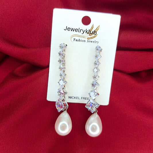 Elegant crystal drop earrings with pearl accents displayed on a Jewelryklub card against a red fabric background
