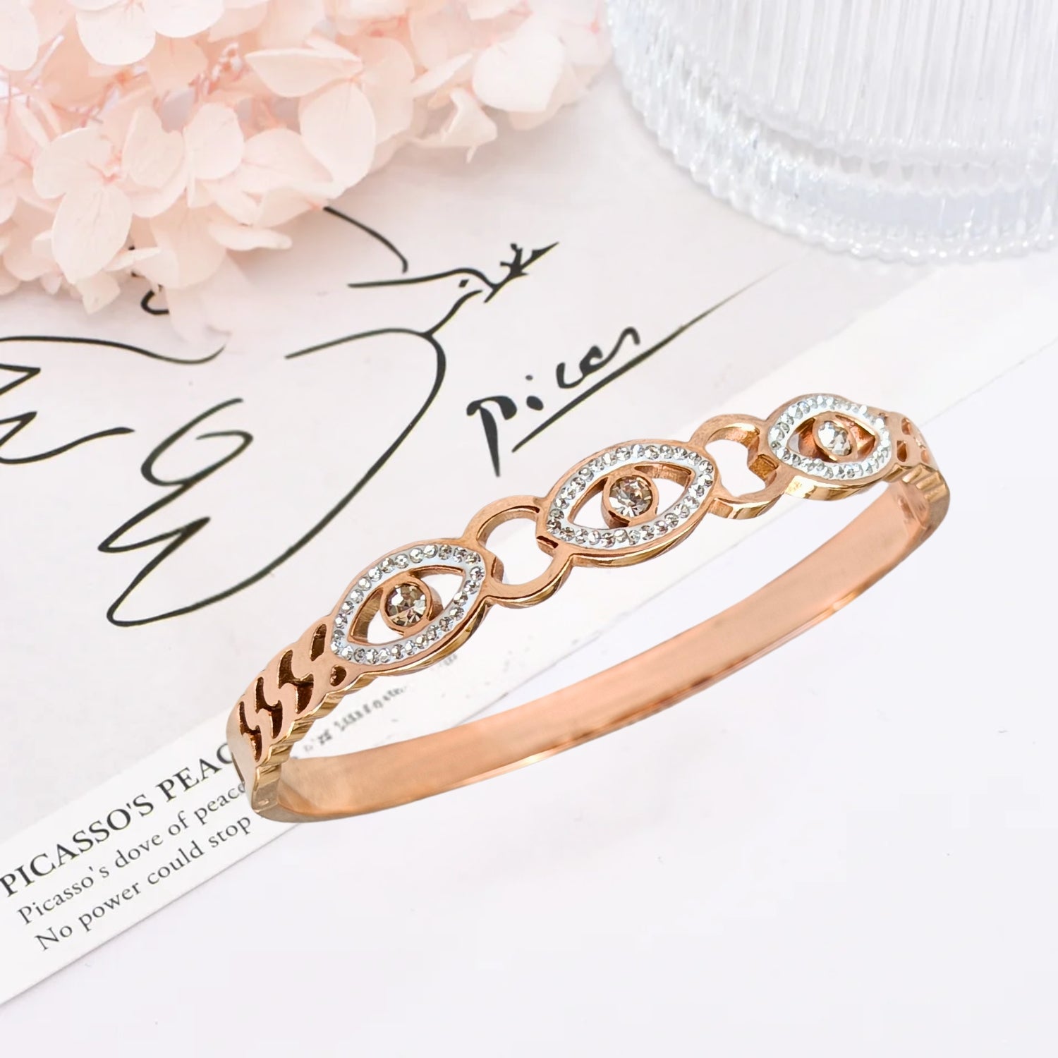 Rose gold evil eye bangle bracelet with intricate crystal detailing, featuring protective eye motifs and a sleek, shimmering finish.