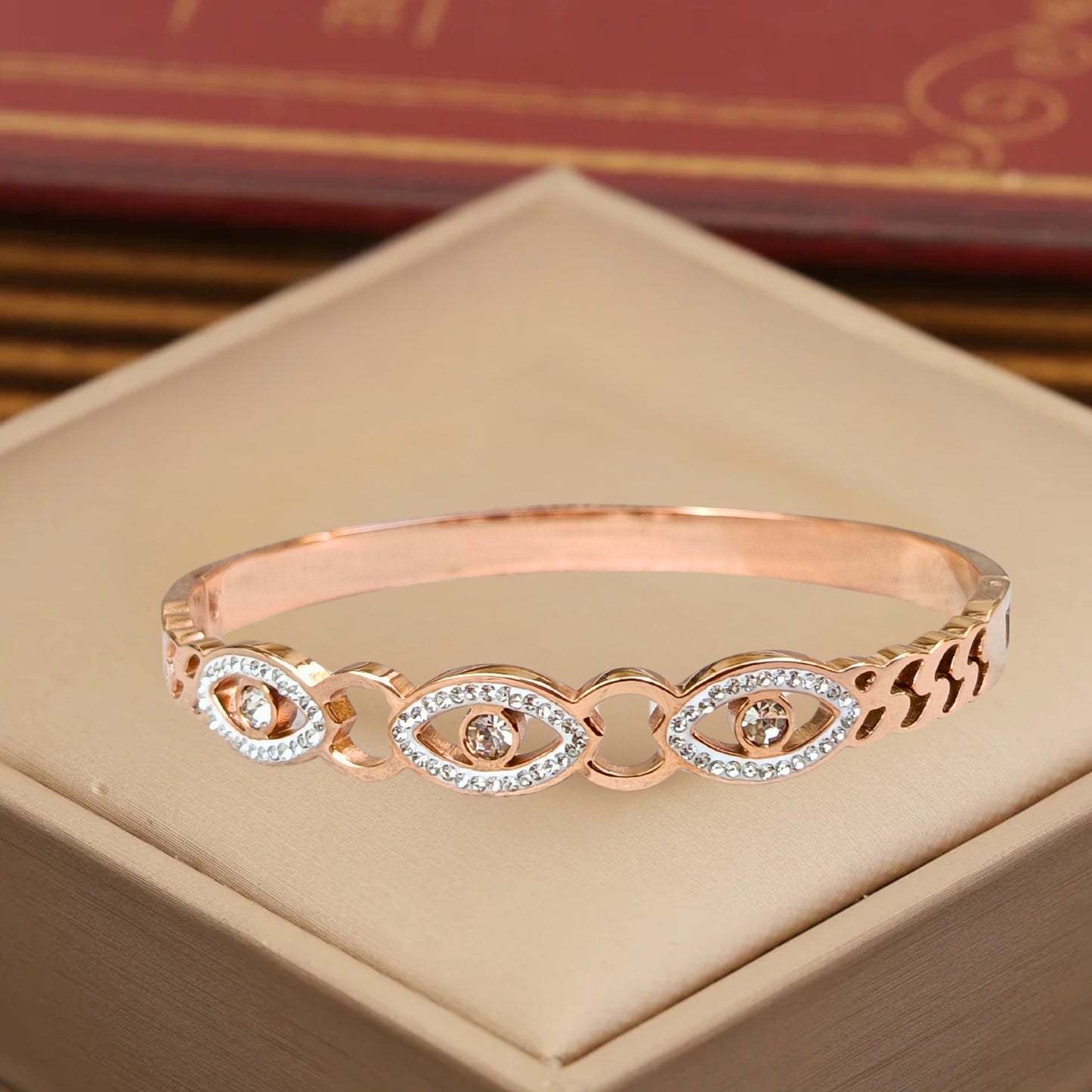 Rose gold evil eye bangle bracelet with intricate crystal detailing, featuring protective eye motifs and a sleek, shimmering finish.