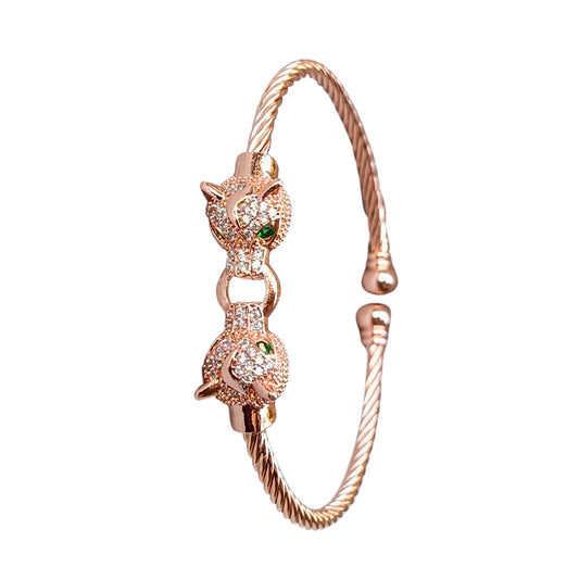 A rose gold cuff bracelet featuring two detailed jaguar heads with emerald-green eyes